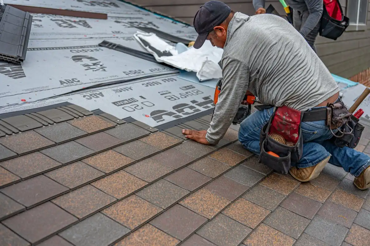 Roofing installer fastening shingles over new underlayment in Marana, AZ